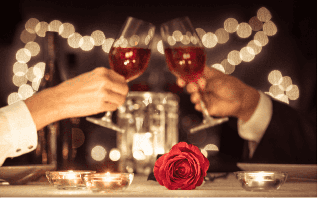 Kaksi viinilasia ja ruusu pöydällä